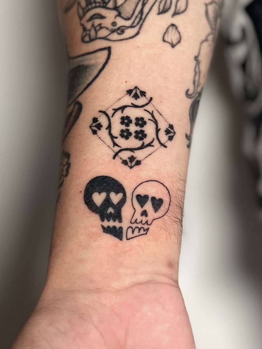 Lovers skulls and Puerto Rican tile flash hand poke tattoos on a wrist