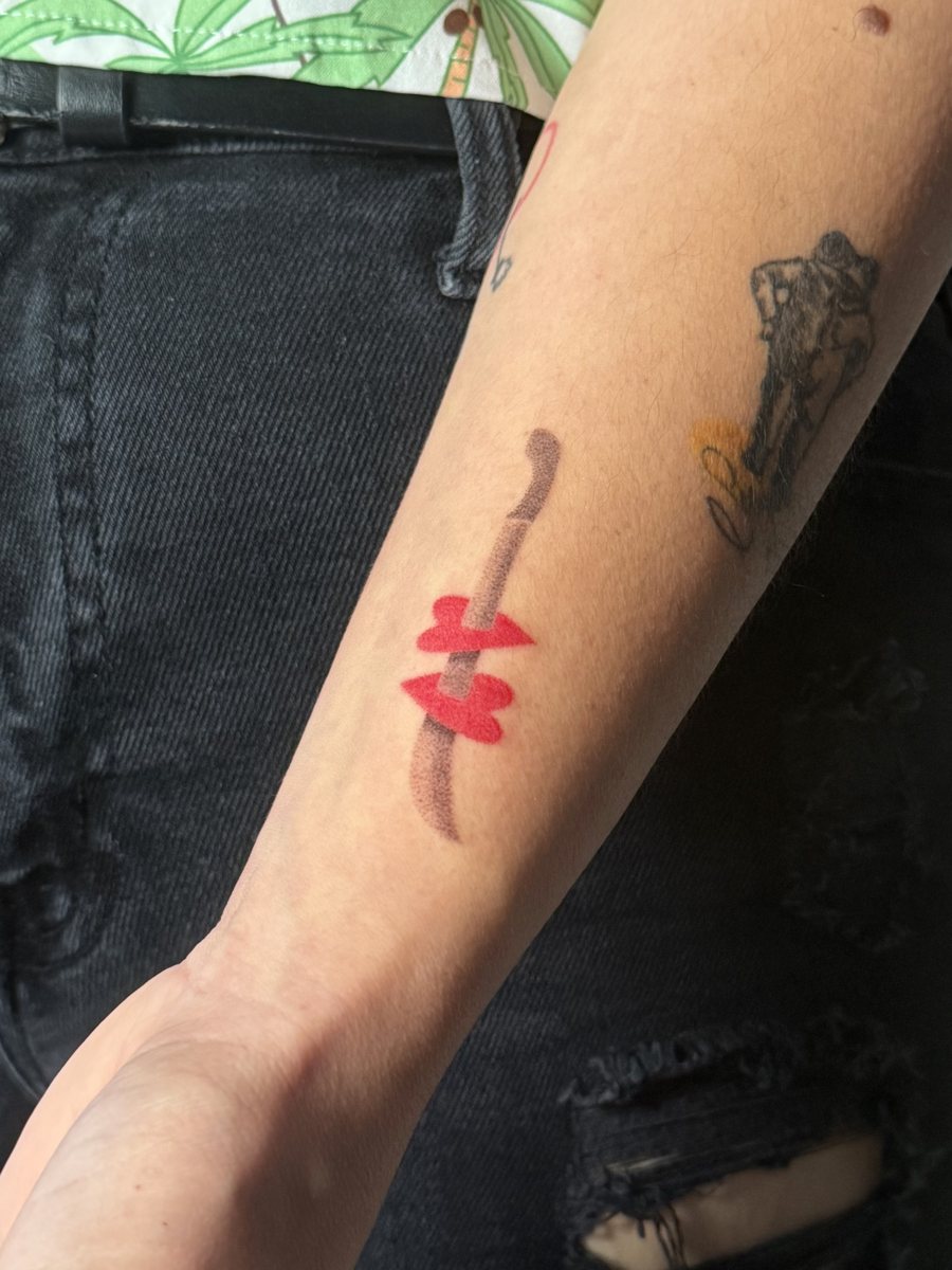 Machete with red hearts hand poke tattoo on a forearm, San Juan